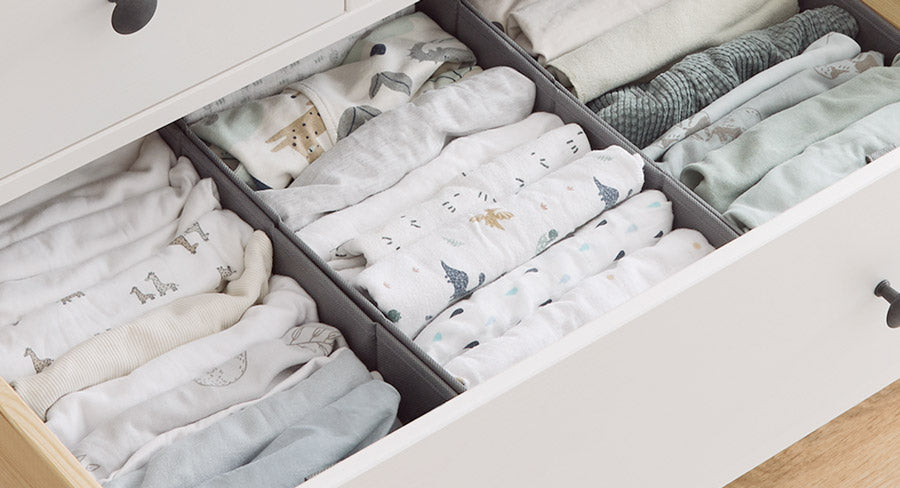 Gefaltete Babykleidung in Organizern, die in einer Schublade verstaut sind.