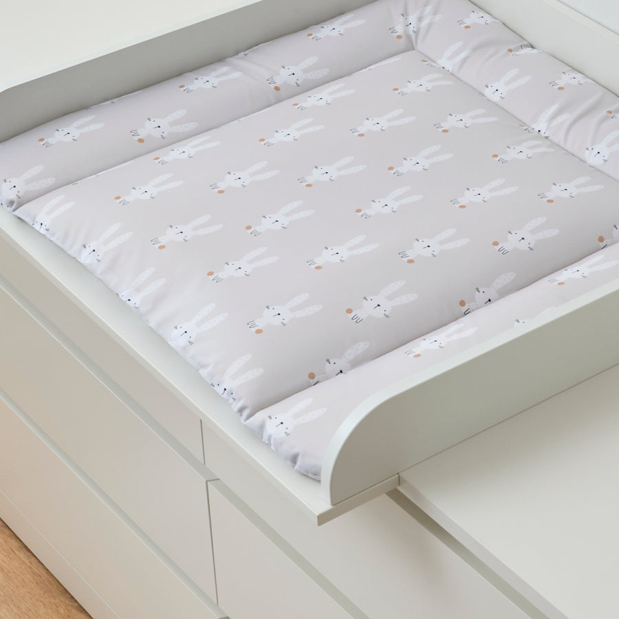 Beige Wickelauflage mit Hasen-Motiven in einem Wickelaufsatz, der auf einer Malm Kommode von IKEA liegt.