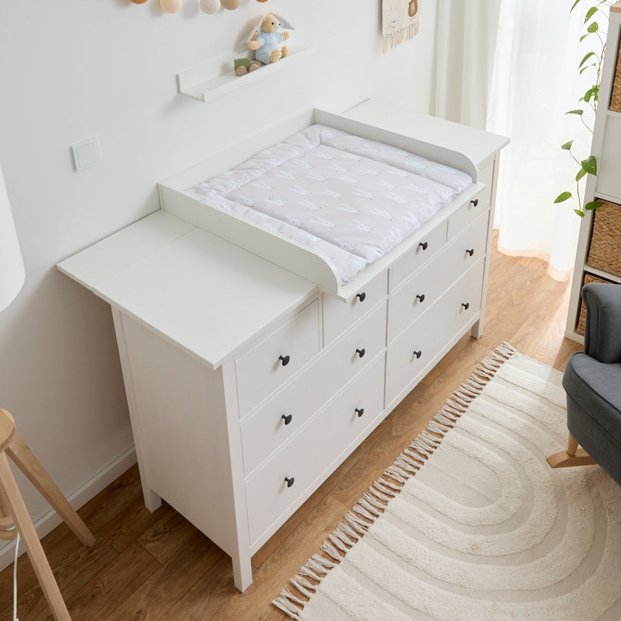 Große Hemnes Kommode mit einem mittig platzierten Wickelaufsatz. Darauf liegt eine beige Wickelunterlage, die genau in den Aufsatz passt.