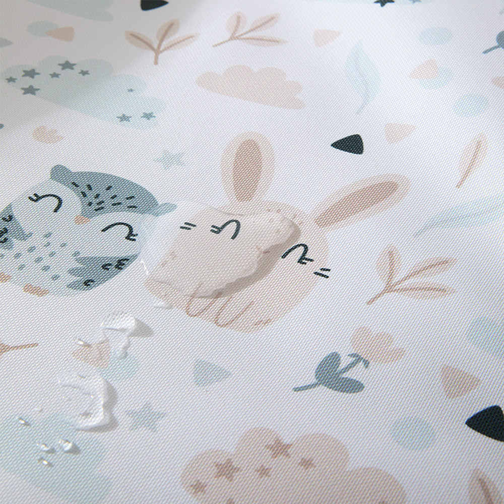 Nahansicht einer wasserabweisenden Wickelauflage mit illustrierten Eulen und Hasen.