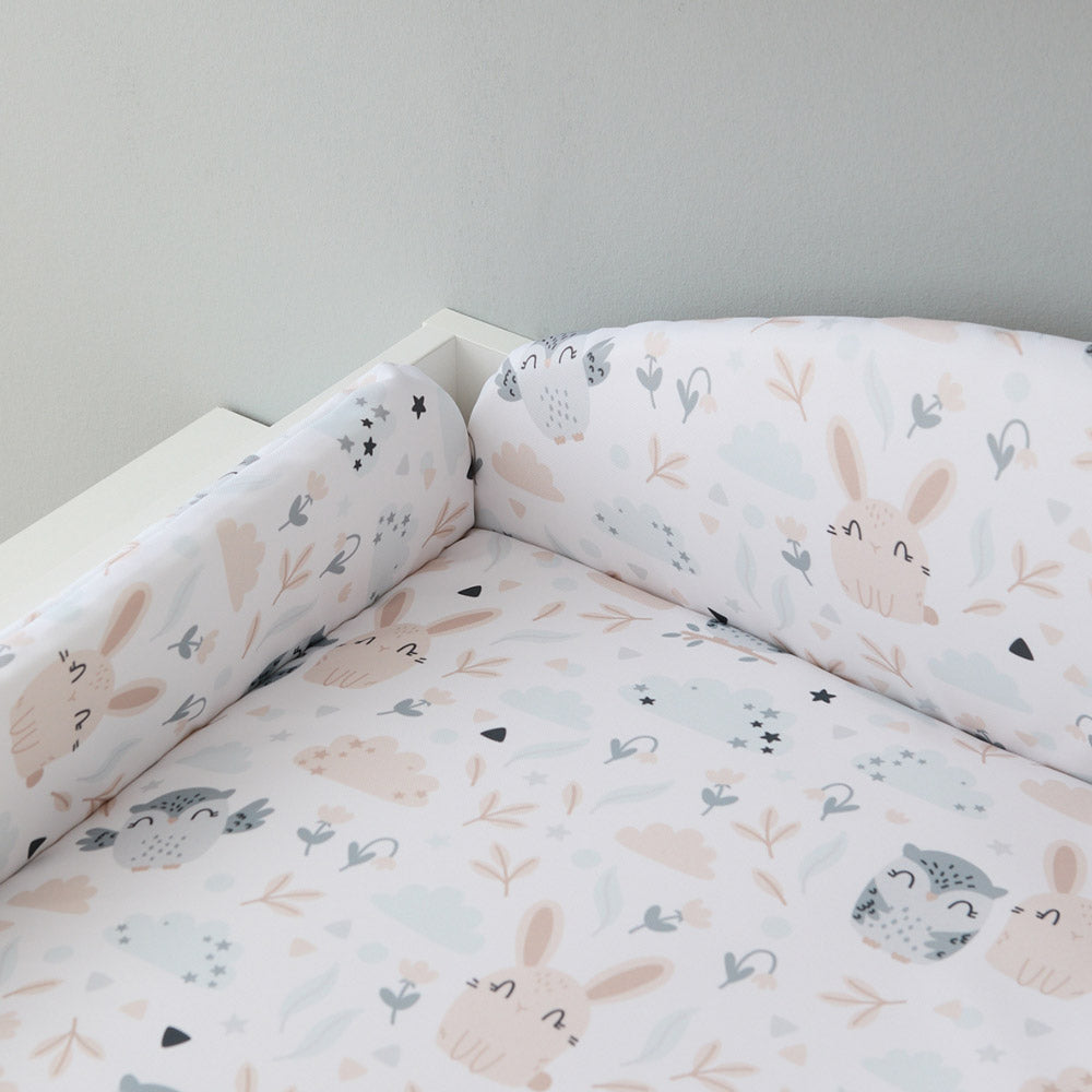 Auf einem Wickelaufsatz liegt eine Wickelauflage mit Umrandung mit Eulen und Hasen.