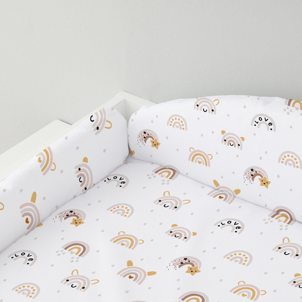 Auf einem Wickelaufsatz liegt eine Wickelauflage mit Umrandung mit Regenbogen-Muster.