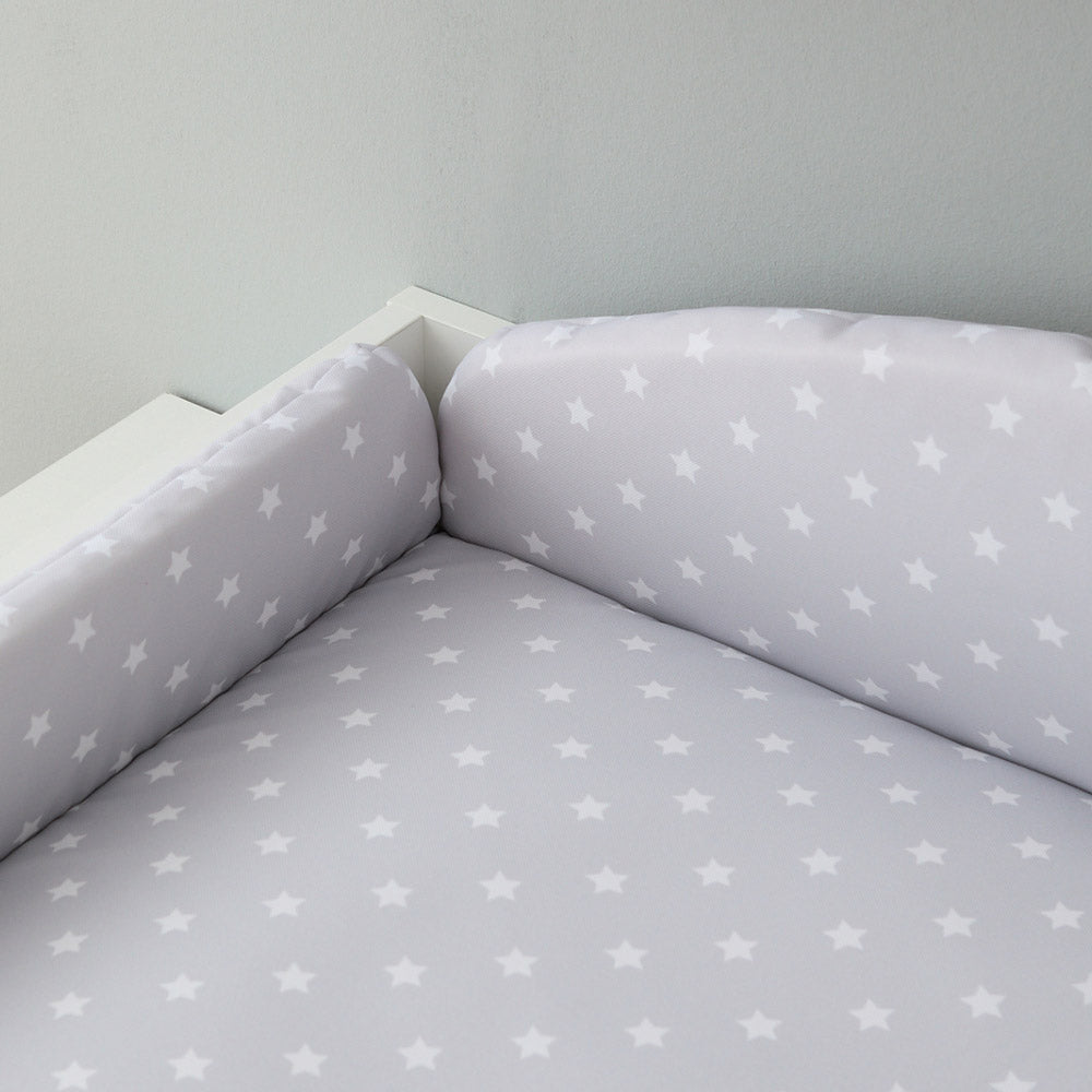 Auf einem Wickelaufsatz liegt eine Wickelauflage mit Umrandung im Sterne-Design.