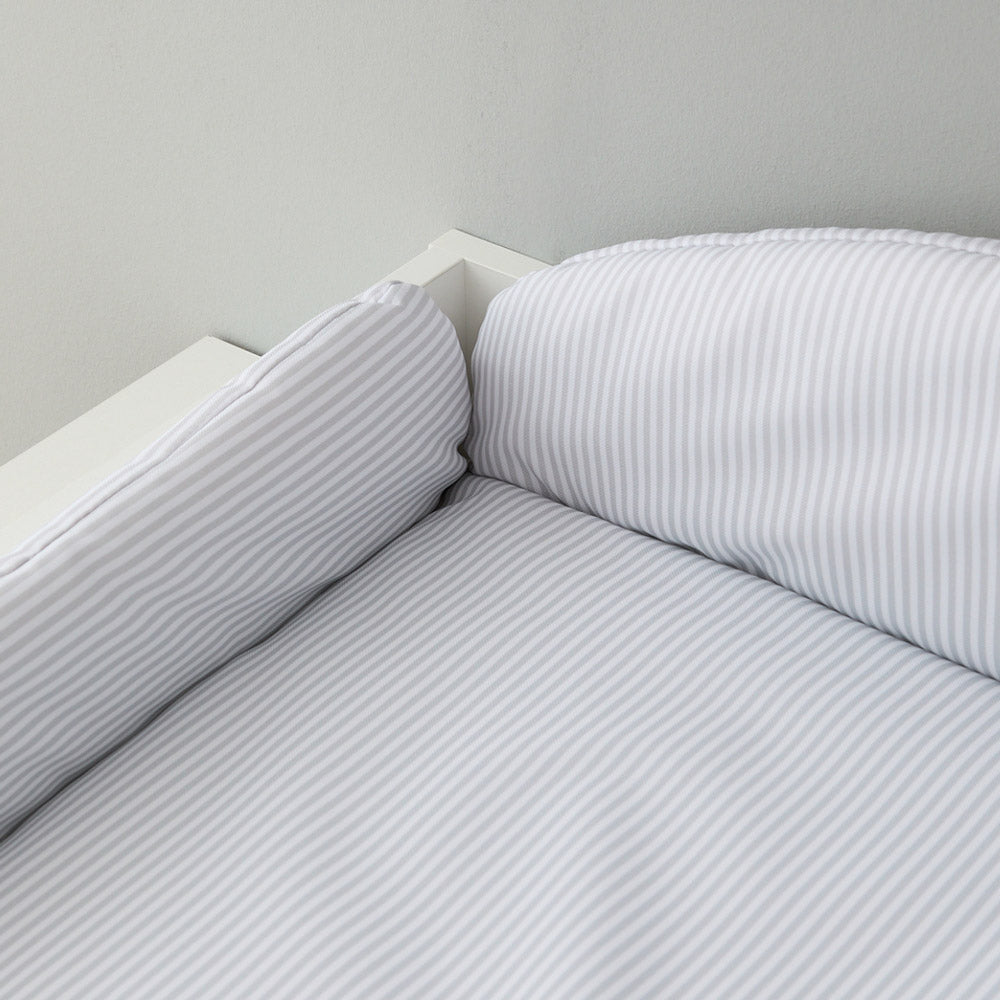 Auf einem Wickelaufsatz liegt eine Wickelauflage mit Umrandung im Streifenmuster.