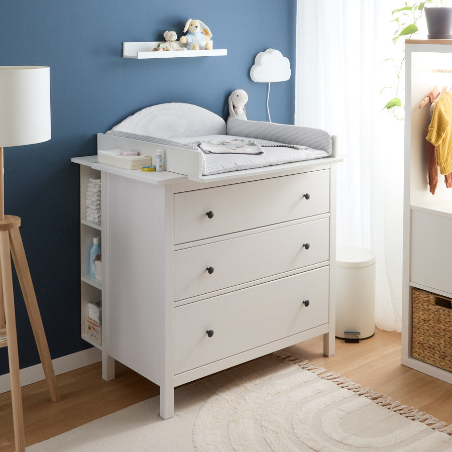 Wickeltisch Set für die Hemnes Kommode mit 3 Schubladen von IKEA mit einem passgenauen Wickelaufsatz und einer Wickelauflage mit Streifenmuster. Außerdem ist an der Rückseite der Kommode ein Stauraumregal montiert.