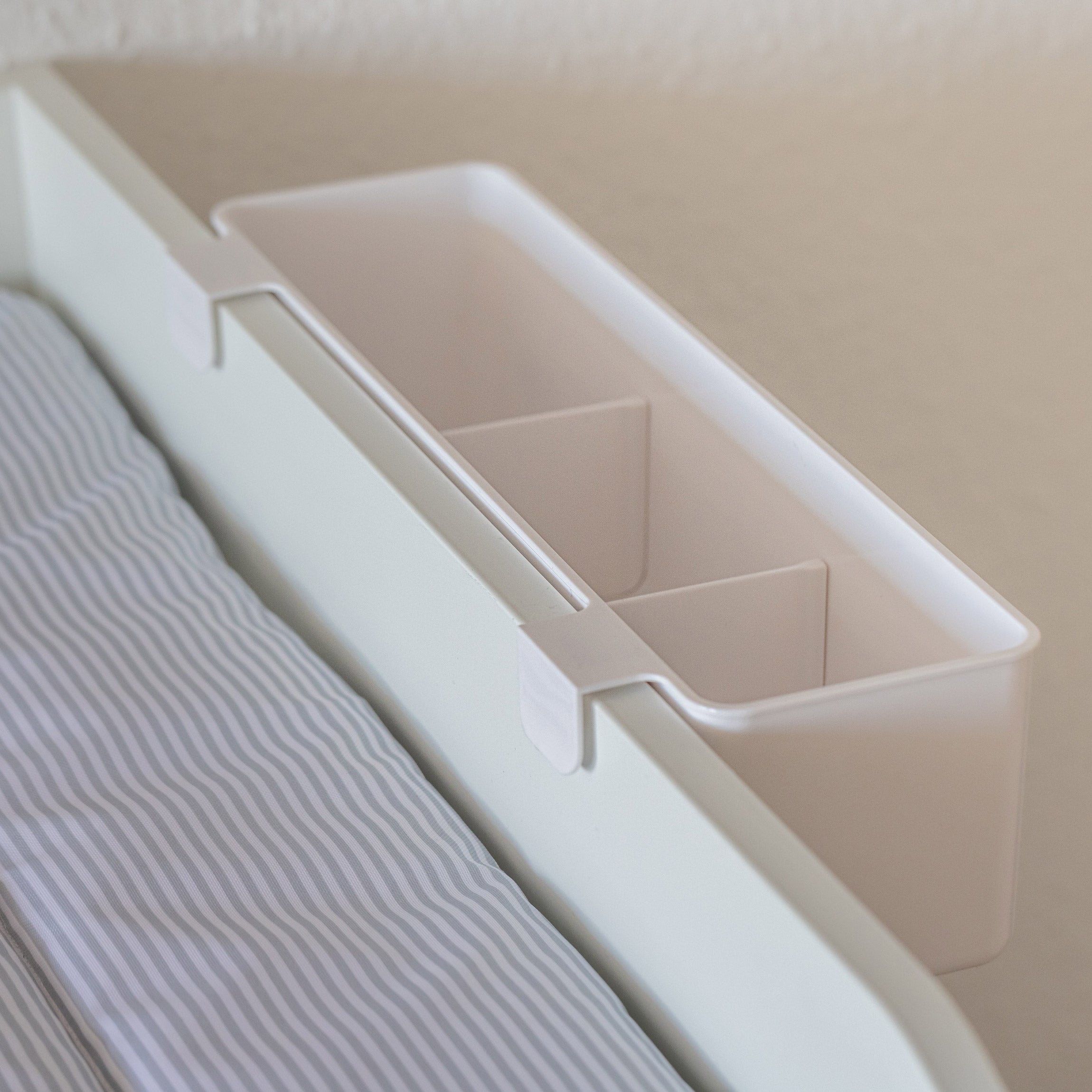 Detailansicht von einem Kunststoff Wickeltisch Organizer mit 2 Zwischenwänden zum Hängen. Der Aufbewahrungsbehälter hängt seitlich an einer Wickelkommode.